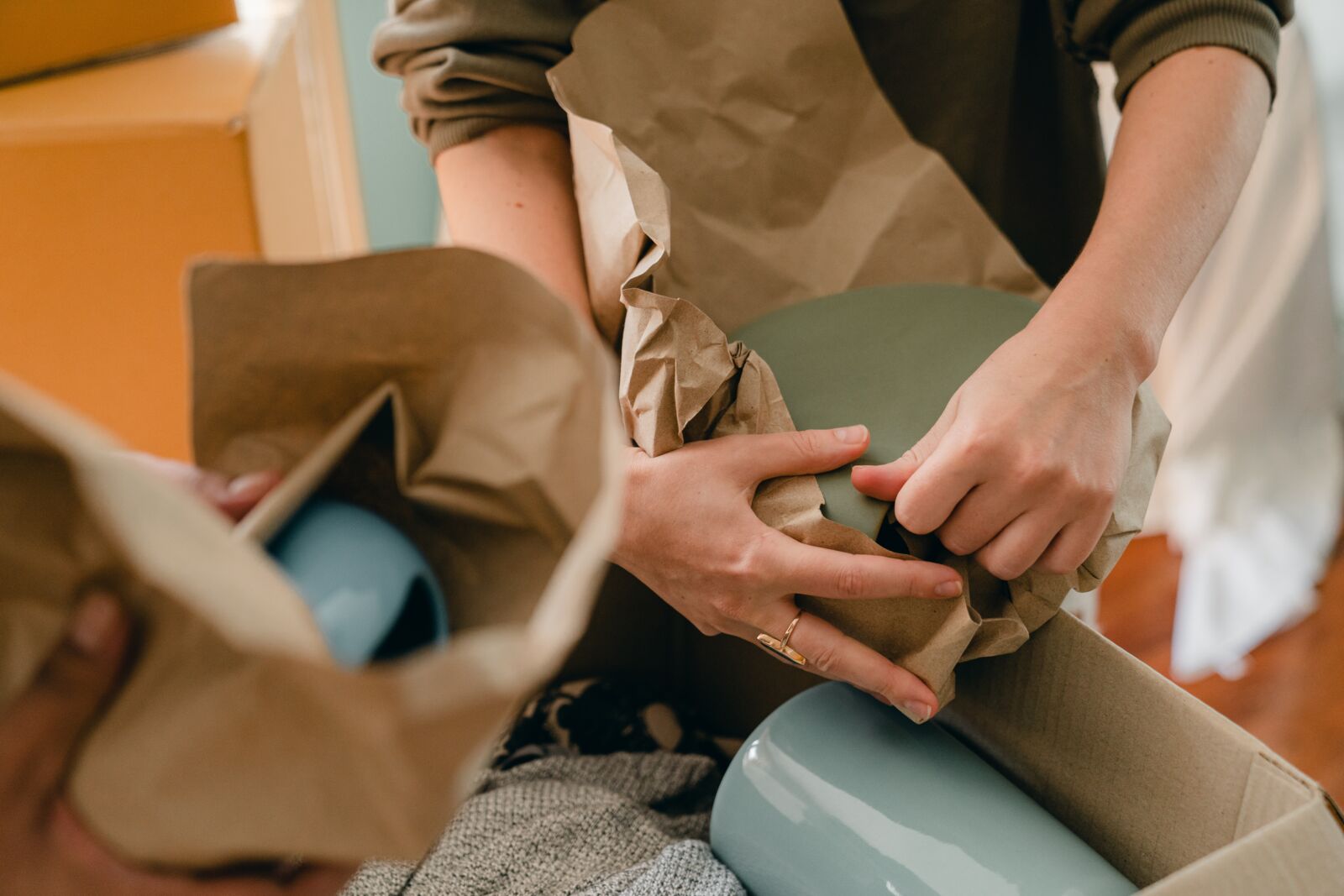 two people packing ceramics in brown paper